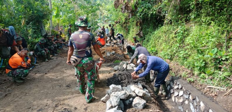Personel Satgas TMMD Bersama Warga Bahu Membahu Kerjakan Senderan Saluran Air.